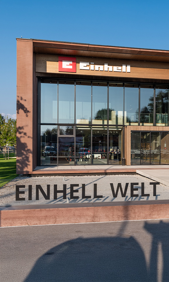Color photo of the modern Einhell building with glass front and the sign “Einhell Welt” in the foreground.