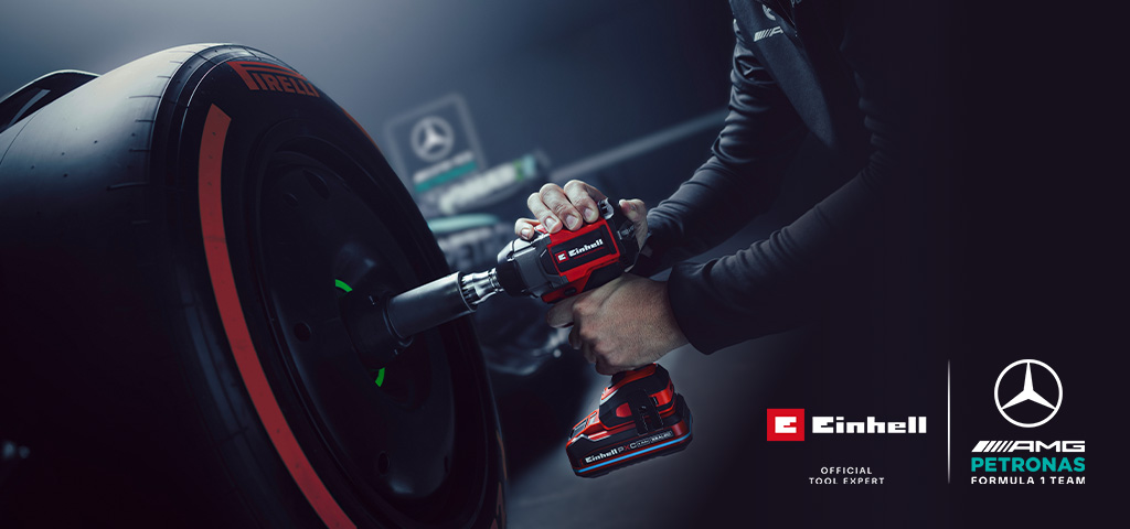Llave de impacto inalámbrica Einhell en uso sobre una rueda de auto, con el branding y el logotipo de colaboración del equipo Mercedes-AMG Petronas de Fórmula 1