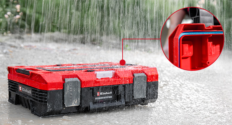 Ein roter Einhell E-Case Werkzeugkoffer steht im Regen; ein runder Ausschnitt zeigt die umlaufende Dichtung am Deckel.