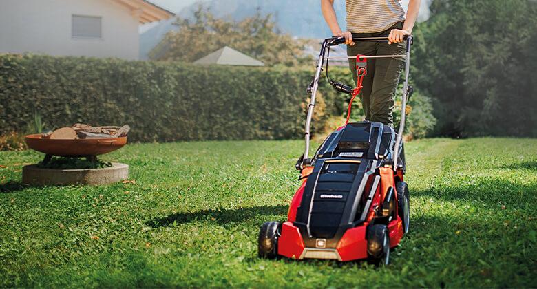 A woman mowing the lawn with an electric Einhell lawn mower