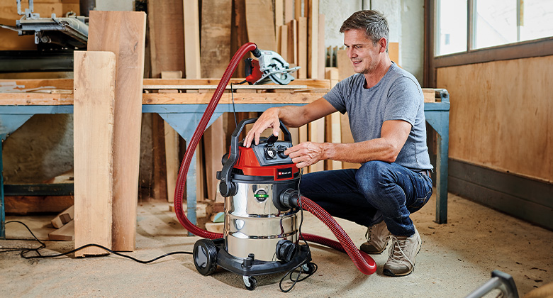 A man uses an corded Einhell wet/dry vacuum in a workshop