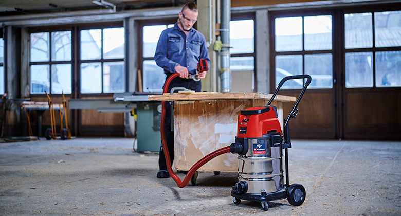 A man uses an Einhell cordless wet/dry vacuum in a workshop